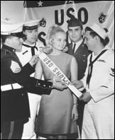 Representatives from the Armed Forces and Judith Ford, Miss America 1969, displayed her temporary new title during contract signing ceremonies at USO National Headquarters in New York.  She went on to do  a 22-day tour to entertain troops in Vietnam.